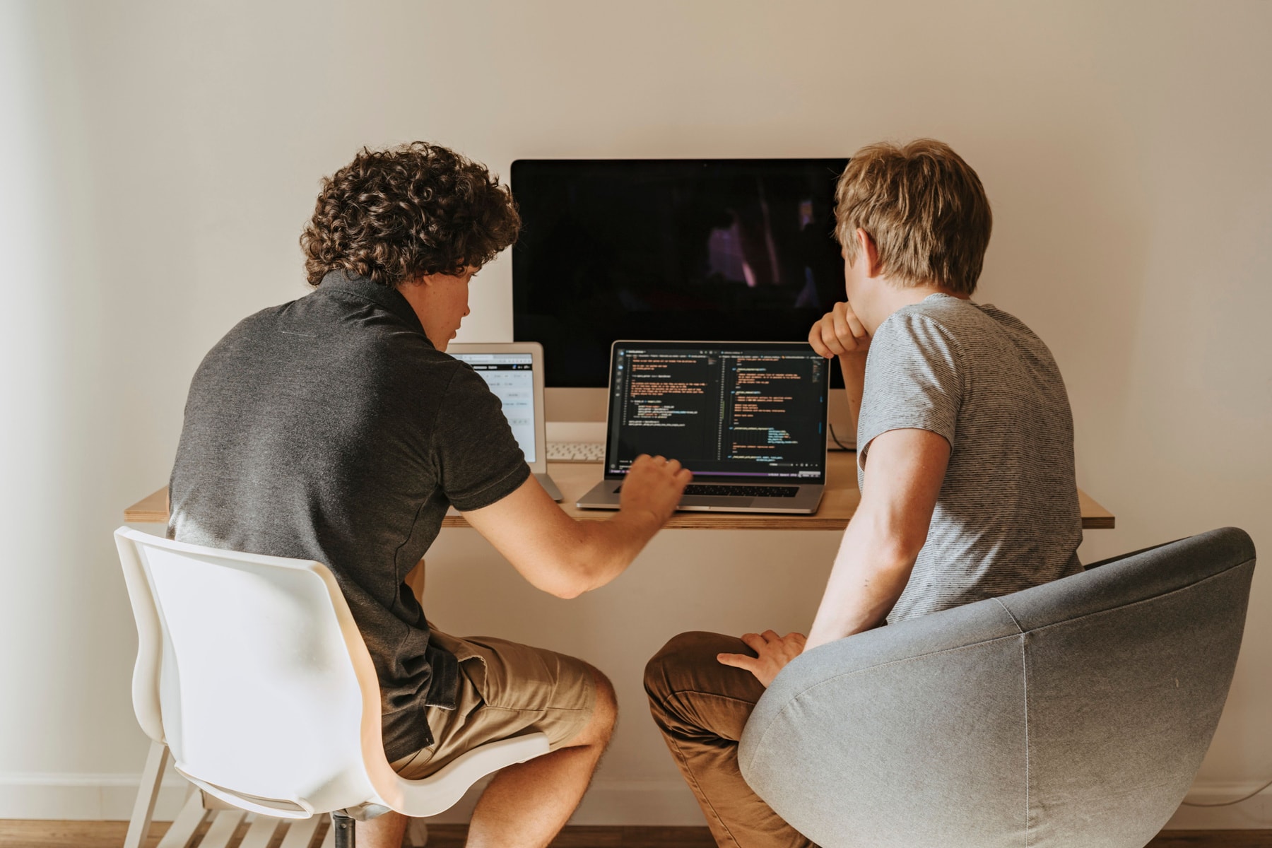 Two Synergy developers reading code on a laptop together